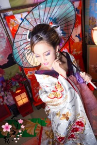 白地に赤・金の刺繍の入った綺麗な打掛を着て和傘を持つ現代風花魁
