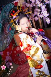 白地に鮮やかな赤色と金色の刺繍の入った打掛を着て和傘を持つ本格古典風花魁